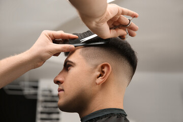 Professional barber making stylish haircut in salon, closeup