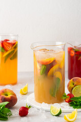 Jugs of fresh refreshing fruit drinks with fruit wedges, summer cold juices with ice