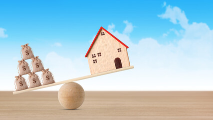Model house on seesaw balancing with stacking coins money on blue sky background. Property investment and home mortgage financial real estate advertising concept