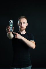 A man holds a voice recorder in his hand. Black background.