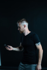 A man holds a voice recorder in his hand. Black background.