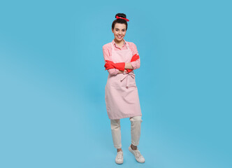 Housewife wearing rubber gloves on light blue background