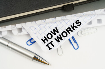 On the table is a pen, notebooks and a crumpled sheet of paper with the inscription - HOW IT WORKS