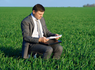 Naklejka na ściany i meble businessman works in a green field, freelance and business concept, green grass and blue sky as background