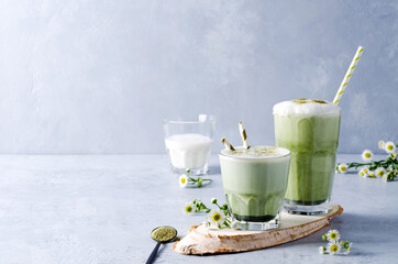 Match tea and coffee latte in glass glasses on a gray concrete background with natural elements, copying space