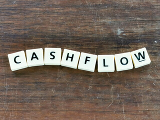 Fototapeta premium Business concept. Text CASH FLOW made of square letter tiles on wooden background.