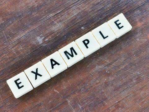 Selective focus diagonal text example made of square letter tiles on wooden background. Business concept.