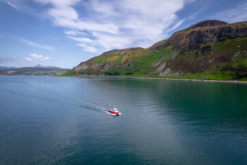 A Red Passenger Ferry Motors Alongside a Beautiful Coastline