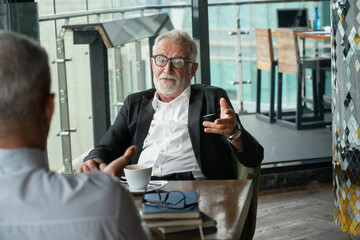 Two businessmen discussing in the corporate high-rise lounge, professional business people meeting.