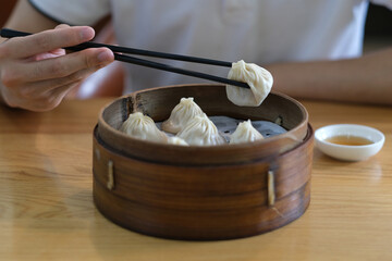 close up hand using chopsticks eating steamed soup buns. Traditional Chinese food