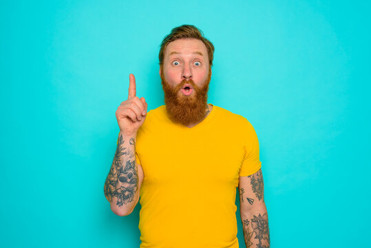 Man with yellow t-shirt and beard is surprised about something