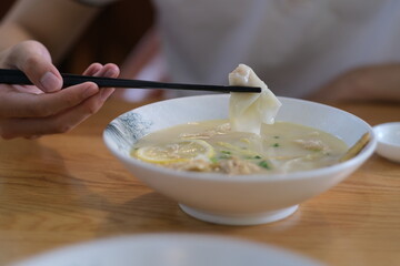 close up hand using chopsticks eating wonton. Traditional Chinese food