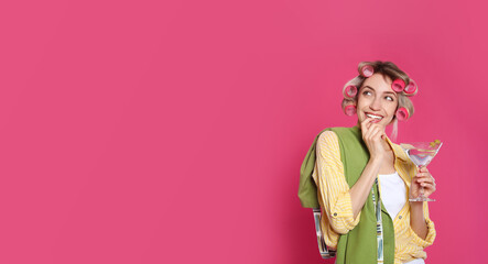 Young housewife with glass of martini on pink background. Space for text