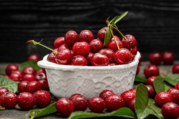 Fresh sweet cherries bowl with leaves on wooden desktop table. water drops on Fresh sour cherry...