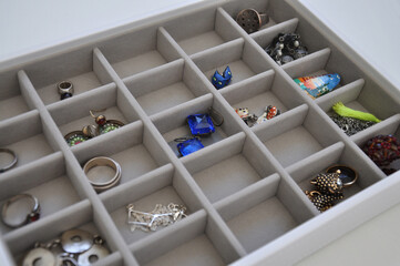 slightly blurred look like with clear details - close-up of a smoky gray sectional velor box with earrings, bracelets and rings