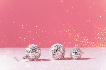 Shiny Christmas toys disco balls on a pink background with sparkles. Composition for holiday christmas card 