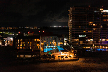 Aerial view of the luxury hotel at night by the sea with a huge infinity pool.