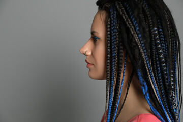 Beautiful young woman with nose piercing and dreadlocks on grey background. Space for text