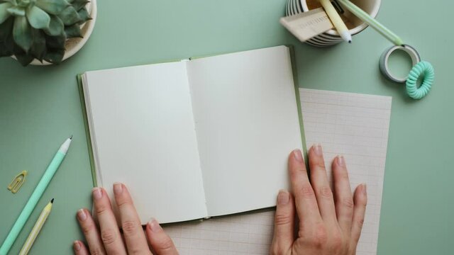 Hands open notebook with clean blank pages on the pastel blue background. Office desk,minimalism.Vertical video frame 9x16