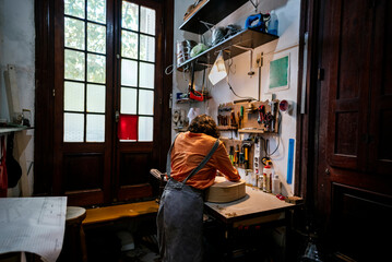 Fototapeta na wymiar Unrecognized young woman in her luthier workshop.