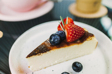 Burnt Strawberry Cheesecake served on white plate with some berries.