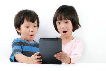 Curious little Asian boy and girl sharing using a tablet computer against a white background