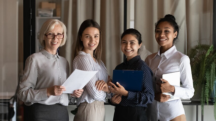 Team of business experts, accounting, legal department staff professional portrait. Multiethnic female employees of different ages holding pads with papers, looking at camera, smiling. Group head shot - Powered by Adobe