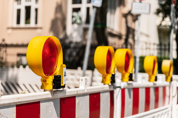 Fünf rote  Baustellenlampen befestigt an einer Absperrung in einem Wohngebiet im Querformat