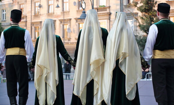 Group of Polish Tatars women and men in traditional costumes stand on their back 