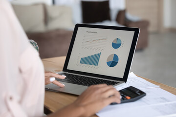 Close up African American woman working financial project with statistics, using laptop and...