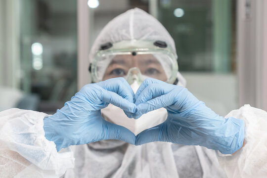 Medical doctor or scientist in lab in ppe personal protective equipment with hands in heart shape for health care, life insurance, organ donor charity donation, world heart health day concept