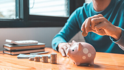 Obraz na płótnie Canvas Man puts a coin dollar in a piggy bank, Saving money for future growth and knowing how to manage your spending wisely, Saving money for business growth or long-term profitability.