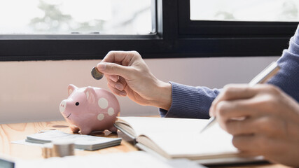 Man puts a coin dollar in a piggy bank, Saving money for future growth and knowing how to manage your spending wisely, Saving money for business growth or long-term profitability.
