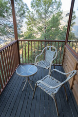 A scenic view of a balcony having wooden railing and easy chairs and an open and green view all around
