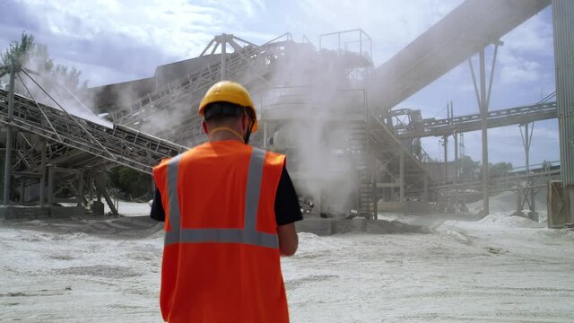 Male engineer walking towards conveyor belts on quarry