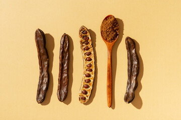 Carob bean and powder flat lay on yellow or brown background