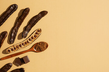 Carob bean and powder flat lay on yellow or brown background