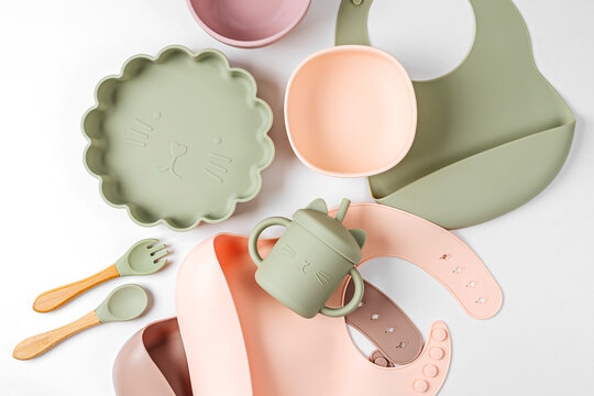 Children's tableware and silicone bibs. Baby accessories. Nutrition and feeding concept. Top view, flat lay