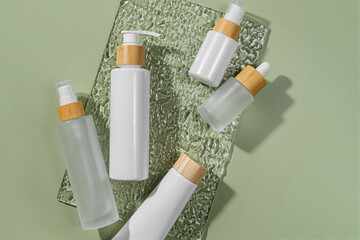 Pump bottle, cream tube, and dropper on green background. Cosmetic container mock-ups. Background...