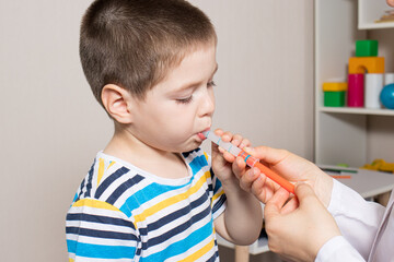 The pediatrician or nurse gives the child syrup in a measuring syringe. Treatment of cough, temperature in children. Paracetamol or ibuprofen for toddlers and preschoolers in pediatrics - obrazy, fototapety, plakaty