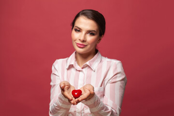 Red heart in beautiful woman hands on pink background