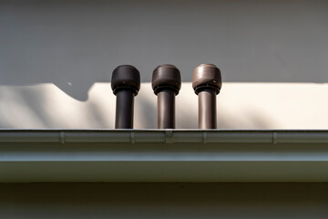 exhaust air pipes and white rain gutter on private house roof. Metallic Guttering System and...