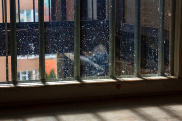 Window with dirty glass and grates . Prison cell with security grates . Low light in the window 