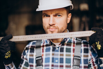 Workman wearing har hat with measuring ruler at factory