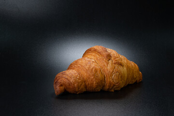 Fresh croissant on a black slate background. Concept for the production and baking of bakery products. Copy space