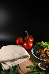 Georgian lavash and shawarma ingredients. Cooking concept. Baking and fast food. Mushrooms, cheese, grilled meat, tomato and cucumber. Vegetables and sauce. Vertical photo. Copy space