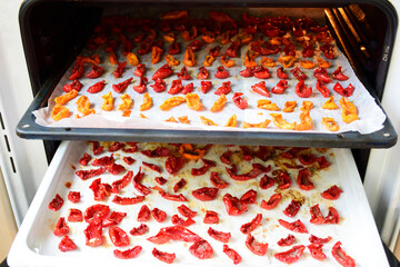 Homemade Dried red tomatoes slices on white baking paper. Traditional Italian Mediterranean kitchen...