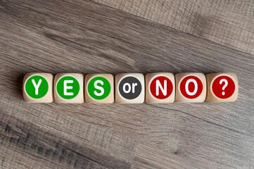 Fototapeta premium Cubes, dice or blocks showing the words YES or NO on wooden background