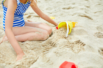 Little kid having fun on the beach and playing with sand toys
