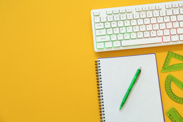 Modern keyboard with RGB lighting and stationery on yellow background, flat lay. Space for text